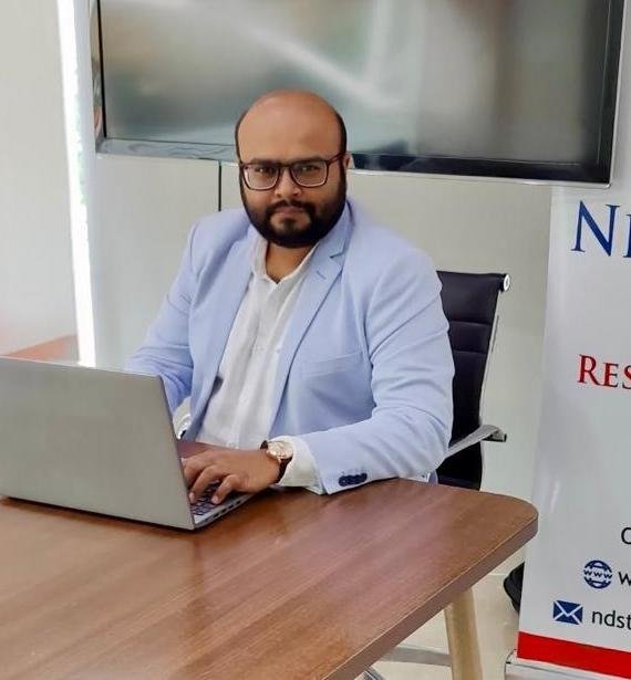 Nirav Desai at his trading desk with market charts on screen